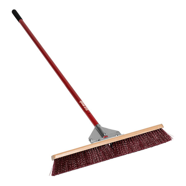 A red and black Kenyon Wonder push broom with a wooden handle.