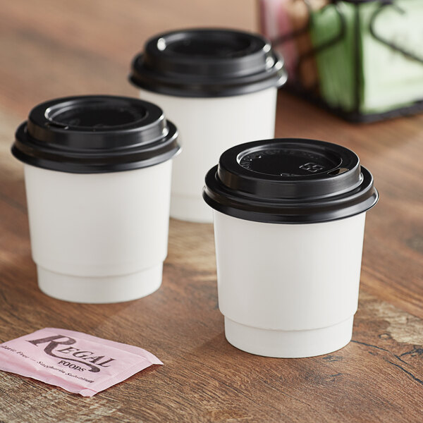 A group of white Choice paper hot cups with black lids.