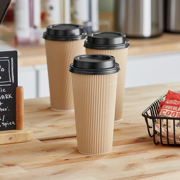 Choice paper hot cups on a counter with a basket of cookies.