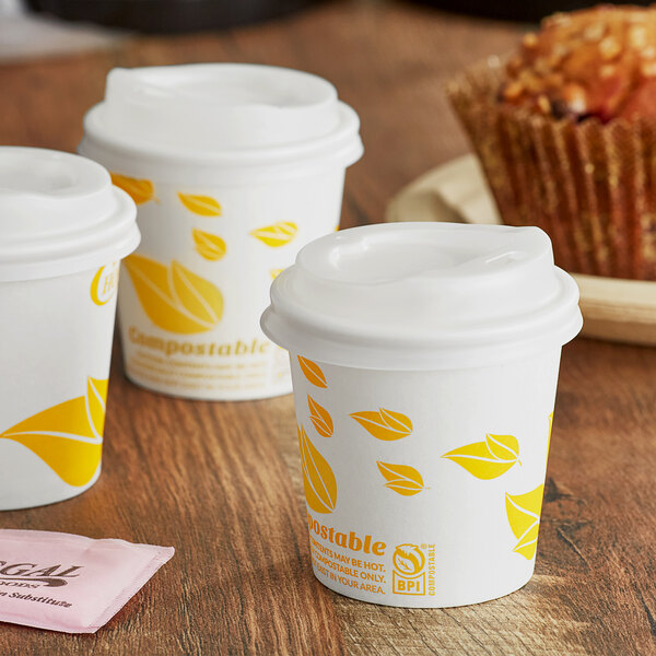 A group of EcoChoice paper hot cups with yellow leaf designs on a table.
