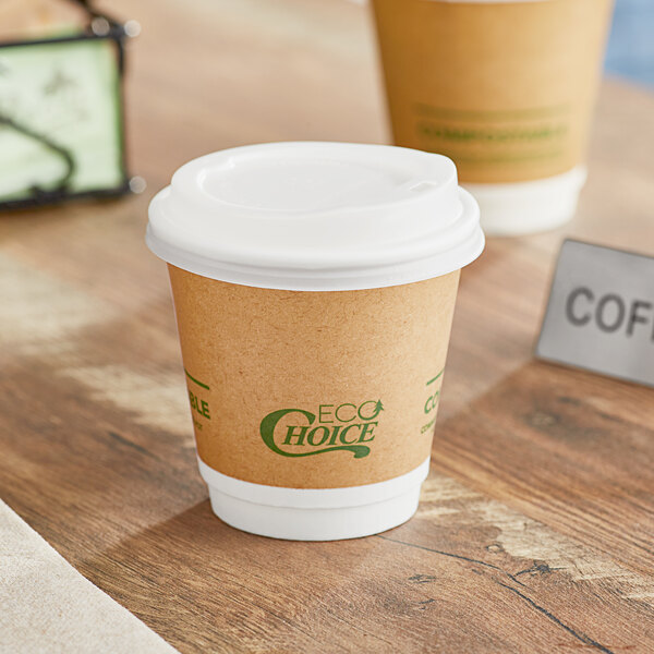 A close-up of an EcoChoice double wall paper coffee cup with a lid on a table in a coffee shop.