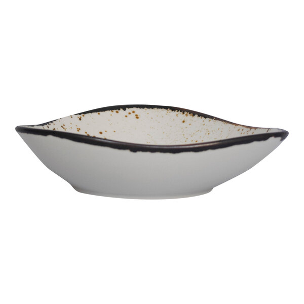 A close up of a white International Tableware triangular stoneware bowl with black speckles.