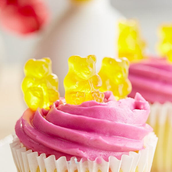 A close up of a cupcake with pink frosting and Albanese Mango Gummi Bears.