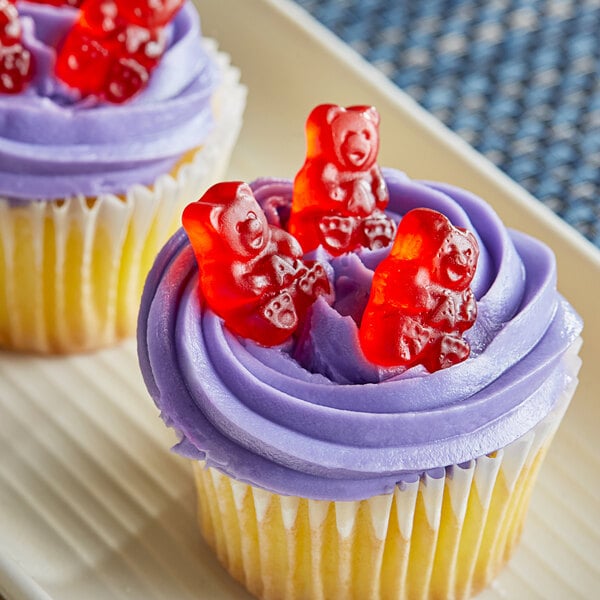 A cupcake with purple frosting and Albanese Wild Cherry Gummi Bears on top.