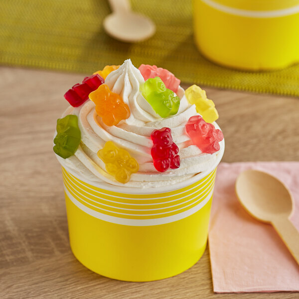 A yellow cupcake with whipped cream and Albanese Gummi Bears on top.