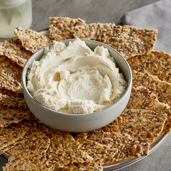A bowl of Don's Salads White Truffle Cream Cheese on a plate of crackers.
