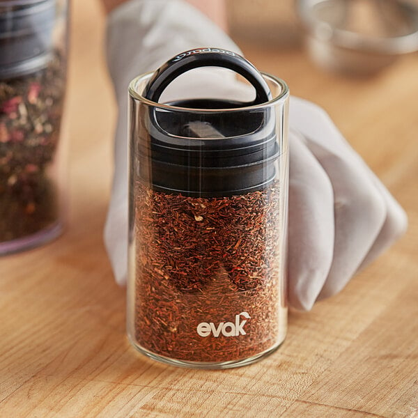 A person holding a Prepara Evak glass container of spices.