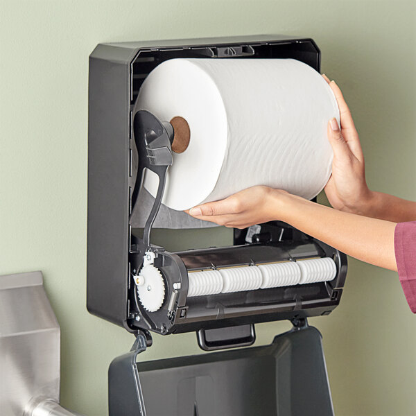 A person holding a roll of Tork white paper towels.