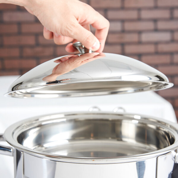 A hand holding a Vollrath Orion chafer cover over a stainless steel pot.