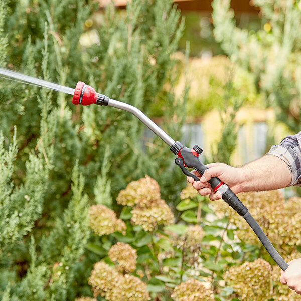 A person using a Chapin watering wand to spray a garden.
