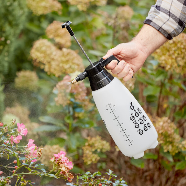 A hand using a Chapin multi-purpose handheld sprayer to spray flowers.