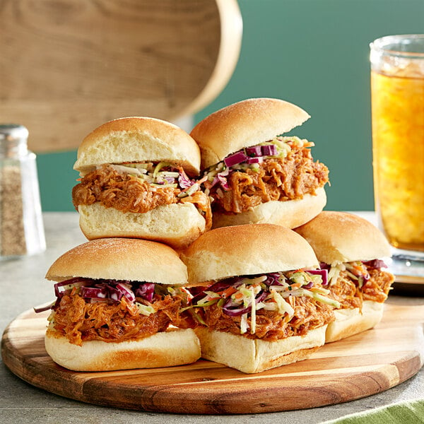 A pulled pork sandwich with coleslaw on a wooden plate.