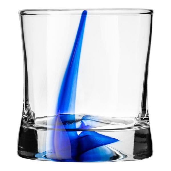 A Libbey rocks glass with blue and white swirls on it filled with blue liquid.