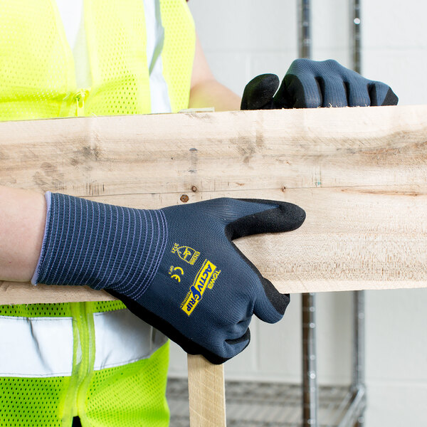 A person wearing Cordova ActivGrip Advance safety gloves holding a piece of wood.