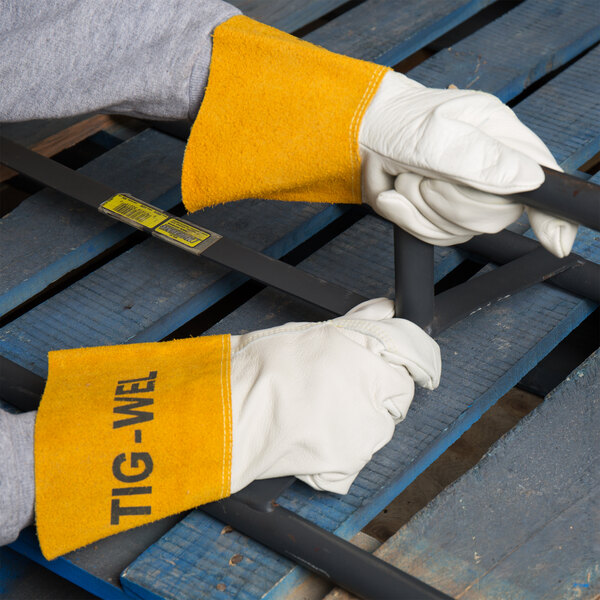 A person wearing Cordova Tig-Wel leather welding gloves holding a metal bar.