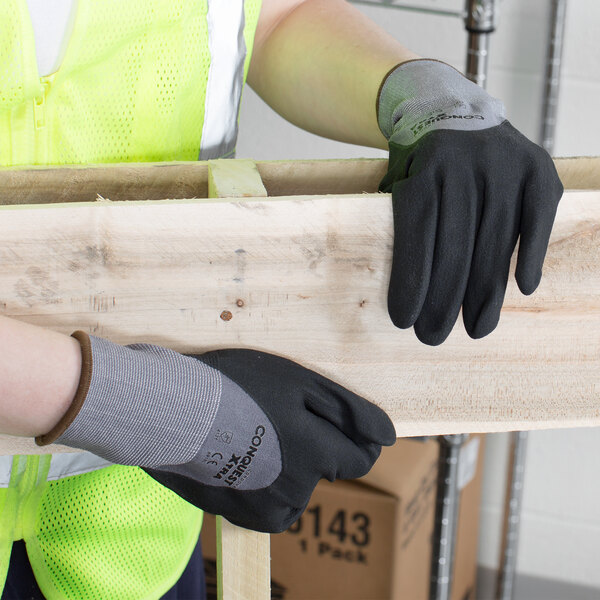 A person wearing Cordova Conquest Xtra gloves holding a piece of wood.