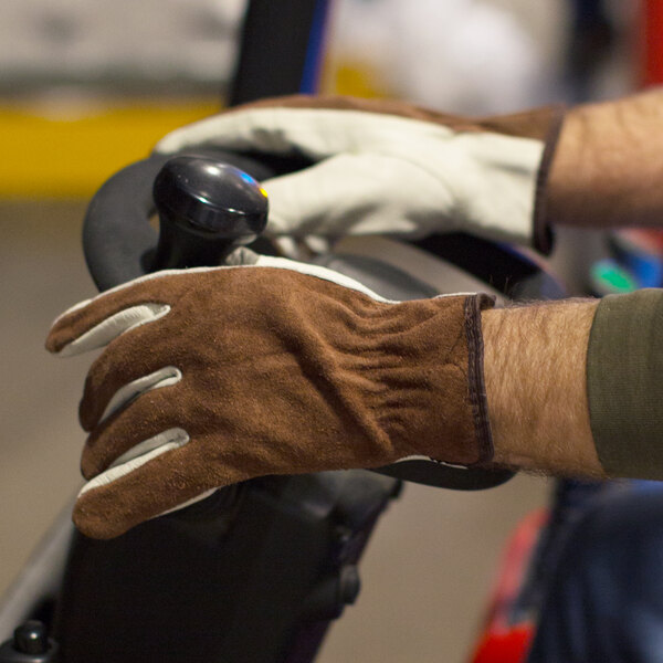 A person wearing Cordova Select Grain Cowhide Leather Driver's Gloves on a vehicle steering wheel.