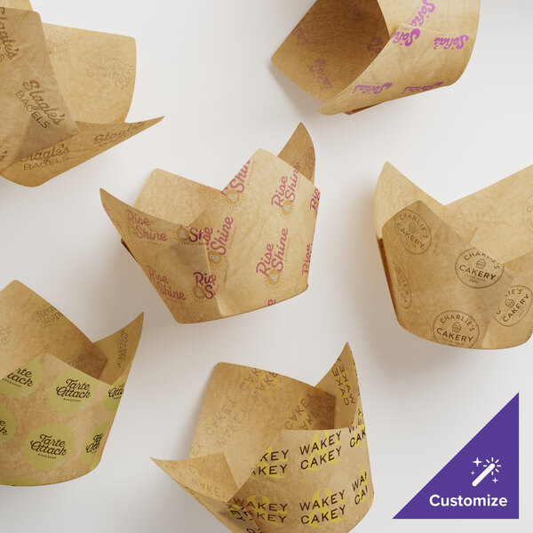 A group of Baker's Lane brown paper tulip-shaped baking cups with black text on the sides.