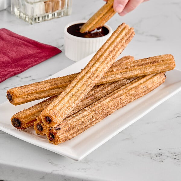 Chocolate filled churros on a plate with chocolate dipping sauce.