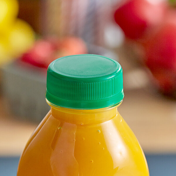 A bottle of orange juice with a dark green tamper-evident cap on a table.