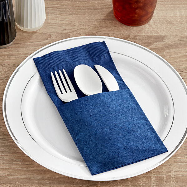A fork and knife placed in a navy blue Hoffmaster Quickset dinner napkin.