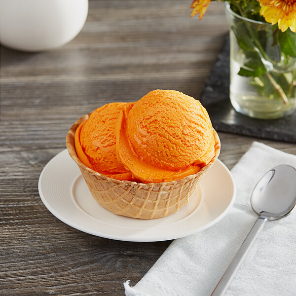 A bowl of I. Rice Tangerine ice cream on a white surface with a spoon.
