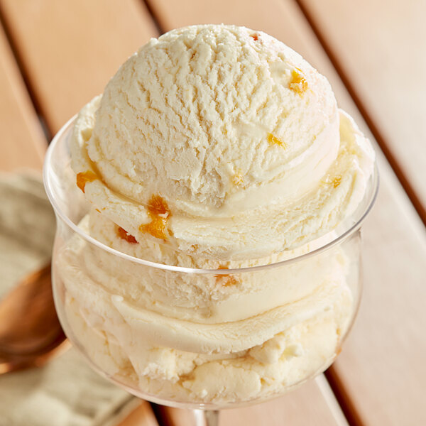 A glass with a scoop of I. Rice peach hard serve ice cream.