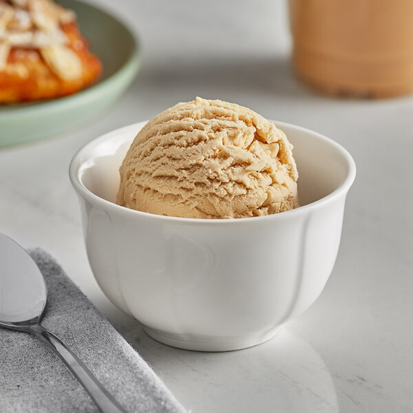 A bowl of I. Rice butter pecan hard serve ice cream with a spoon.