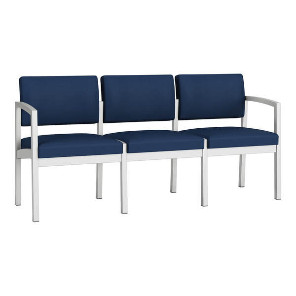 A Lesro Lenox steel sofa with navy blue vinyl upholstery and white legs.