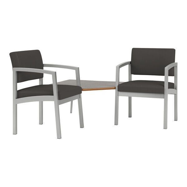 Two Lesro Lenox steel arm chairs with black vinyl cushions and a corner table with a white laminate top.