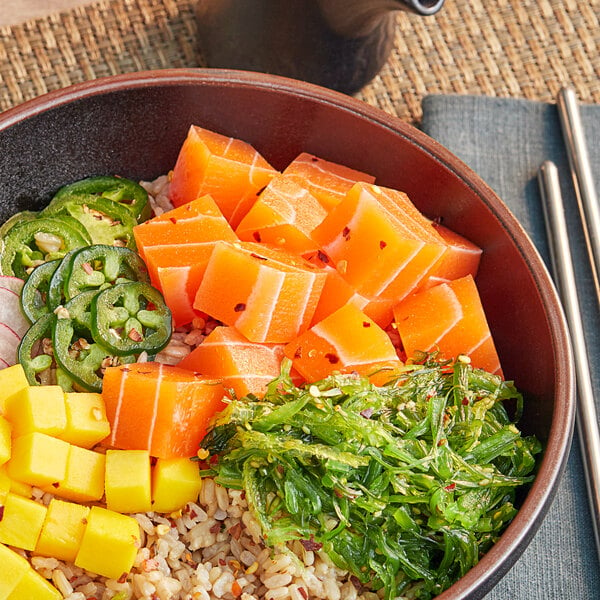 A bowl of Beleaf vegan salmon sashimi with rice and vegetables with chopsticks.