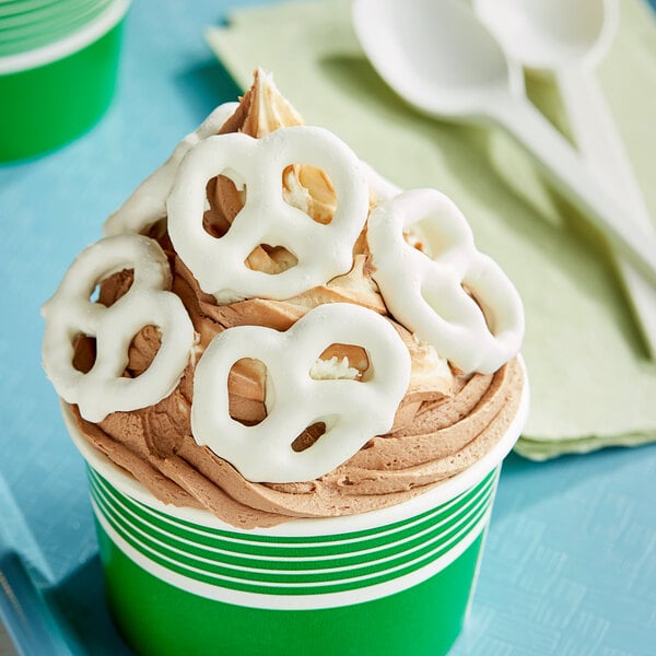 A cup of ice cream with yogurt covered pretzels on top.