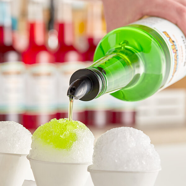 A person pouring Hawaiian Shaved Ice Margarita syrup into a cup of snow cone ice.