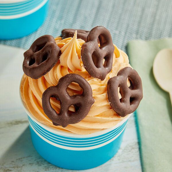 A chocolate covered pretzel on a frosted dessert.