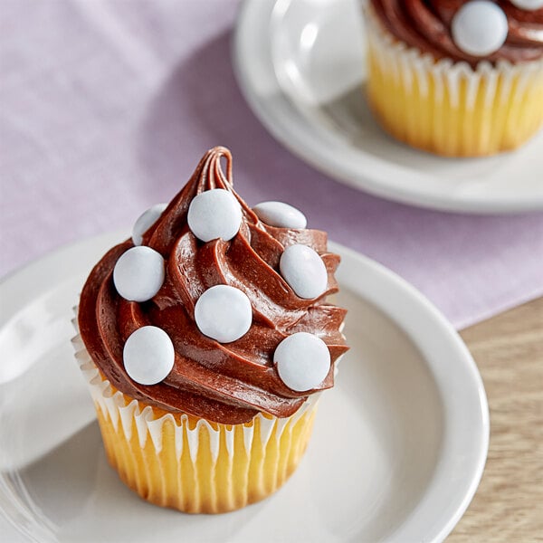 A chocolate cupcake with chocolate frosting and white candies on top.
