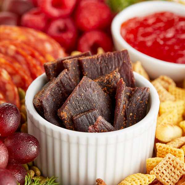 A bowl of Bronco Billy's beef jerky and other snacks on a table.