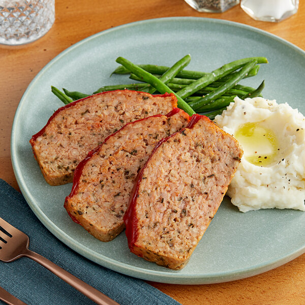 A plate with meatloaf, mashed potatoes, and green beans with Impossible Foods plant-based ground pork on it.