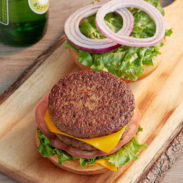 Two Impossible Foods plant-based vegan burgers on a wooden board.