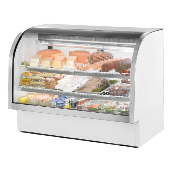 A True white curved glass refrigerated deli case filled with different types of meats.