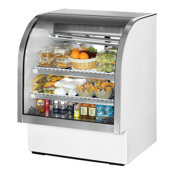 A True white curved glass refrigerated deli case full of food.