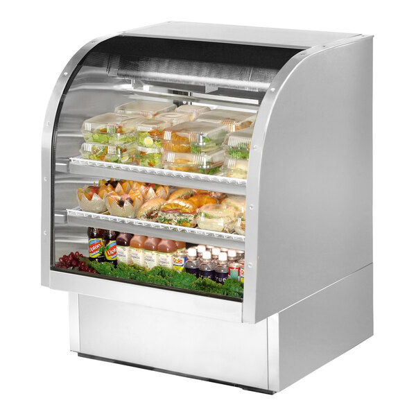 A True stainless steel curved glass refrigerated deli case full of food.
