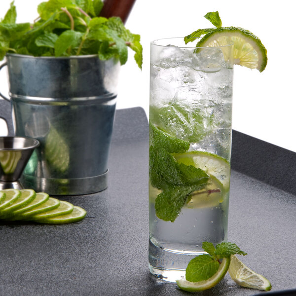 A Stolzle New York Collins Glass filled with water, limes, and mint leaves.