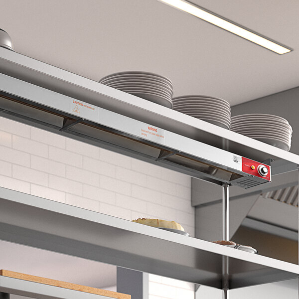 An Avantco stainless steel strip warmer shelf with plates on it.