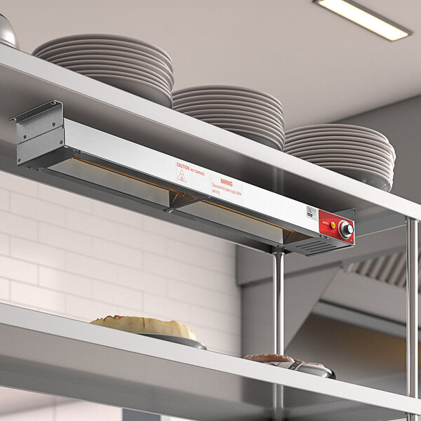 An Avantco strip warmer on a shelf with plates and dishes.