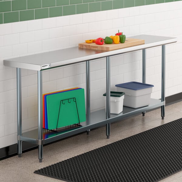 A stainless steel work table with a lower shelf, holding cutting boards and storage containers, with vegetables and a cutting board on top.