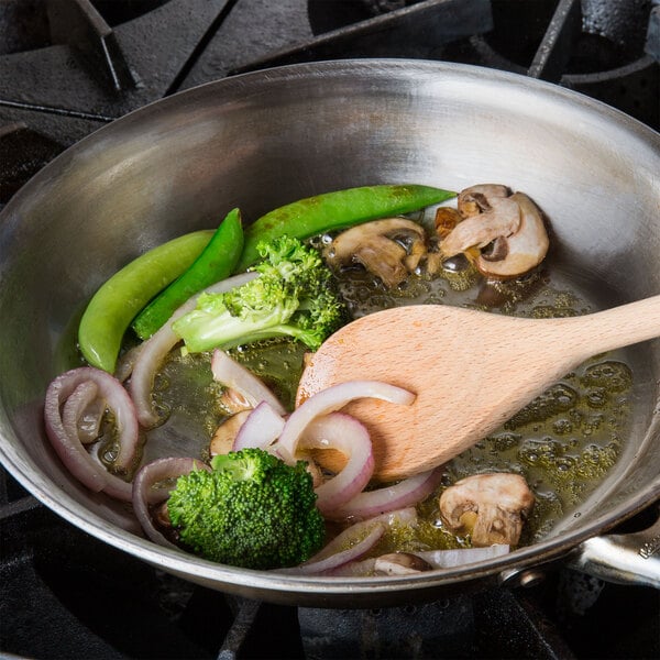 A pan with vegetables cooking in AAK Oasis cooking oil on a stove.