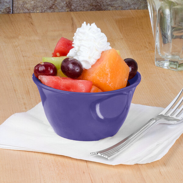 A purple Thunder Group melamine bowl filled with fruit and whipped cream with a fork.