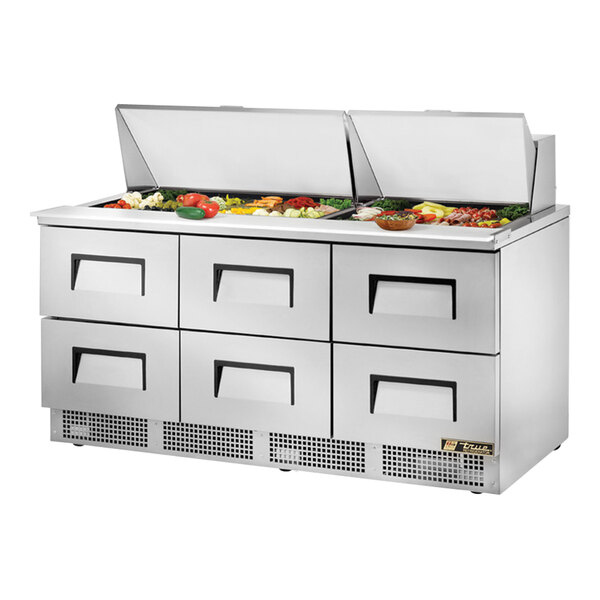 A True 6 drawer mega top refrigerated sandwich prep table on a food buffet with food on top.