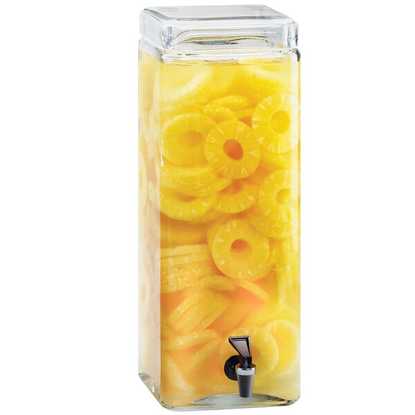 A Cal-Mil glass beverage dispenser with pineapple rings in it.