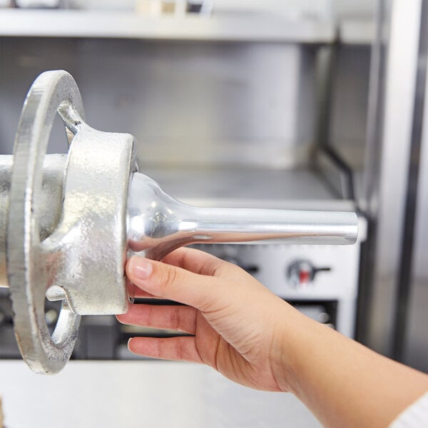 A hand holding a Hobart #32 Large Stuffing Horn for a meat grinder.